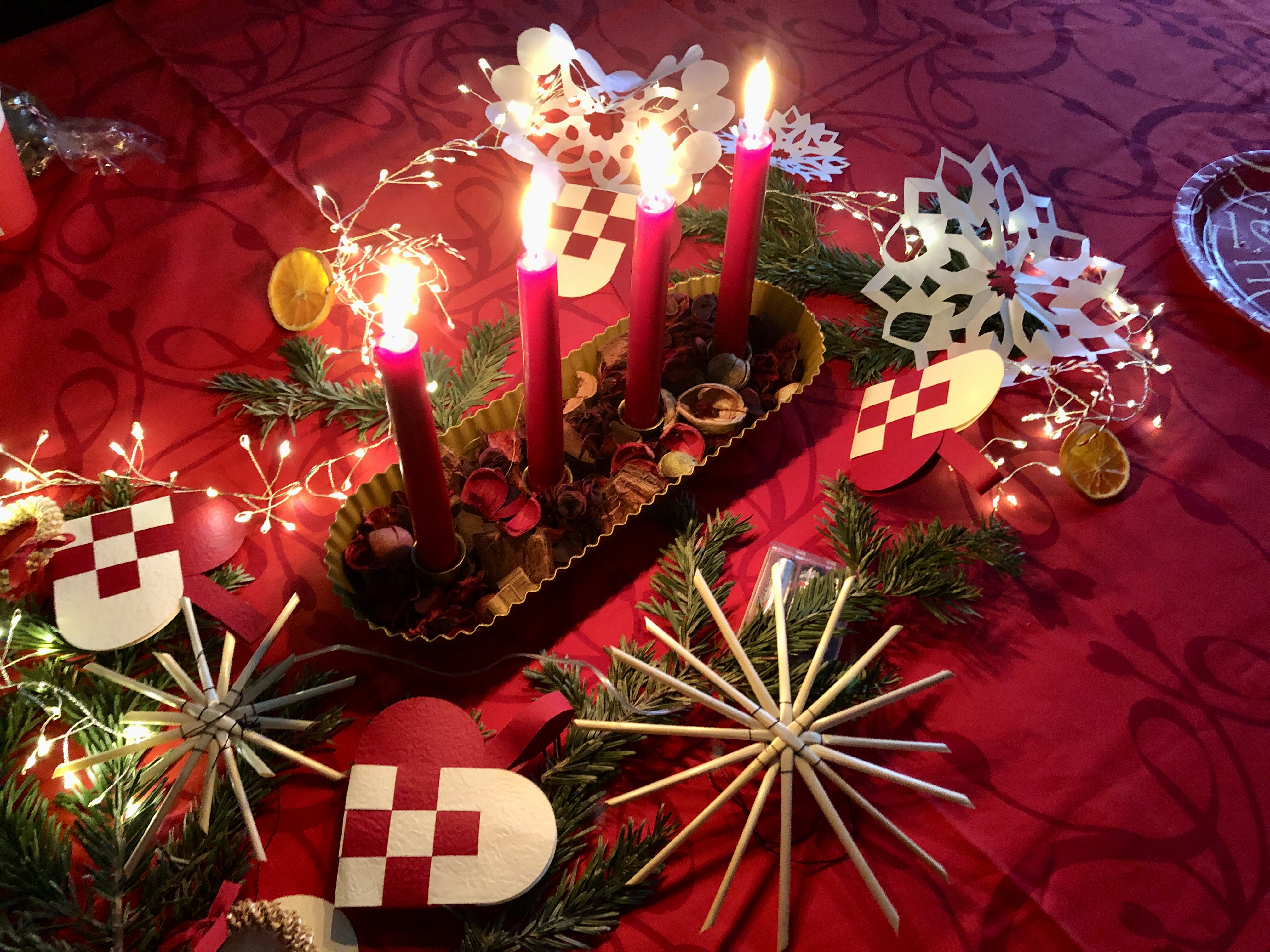 Four candles surrounded by Christmas decorations.