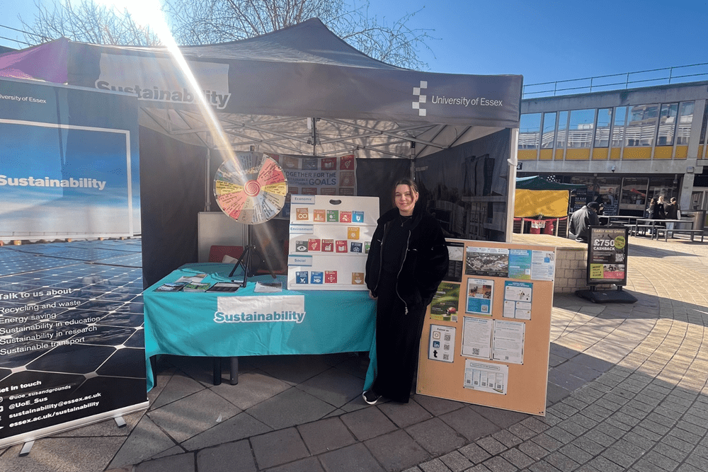 Sustainability Intern Yasmin Hoey standing in front of the sustainability stall during Sustainability Awareness Week 