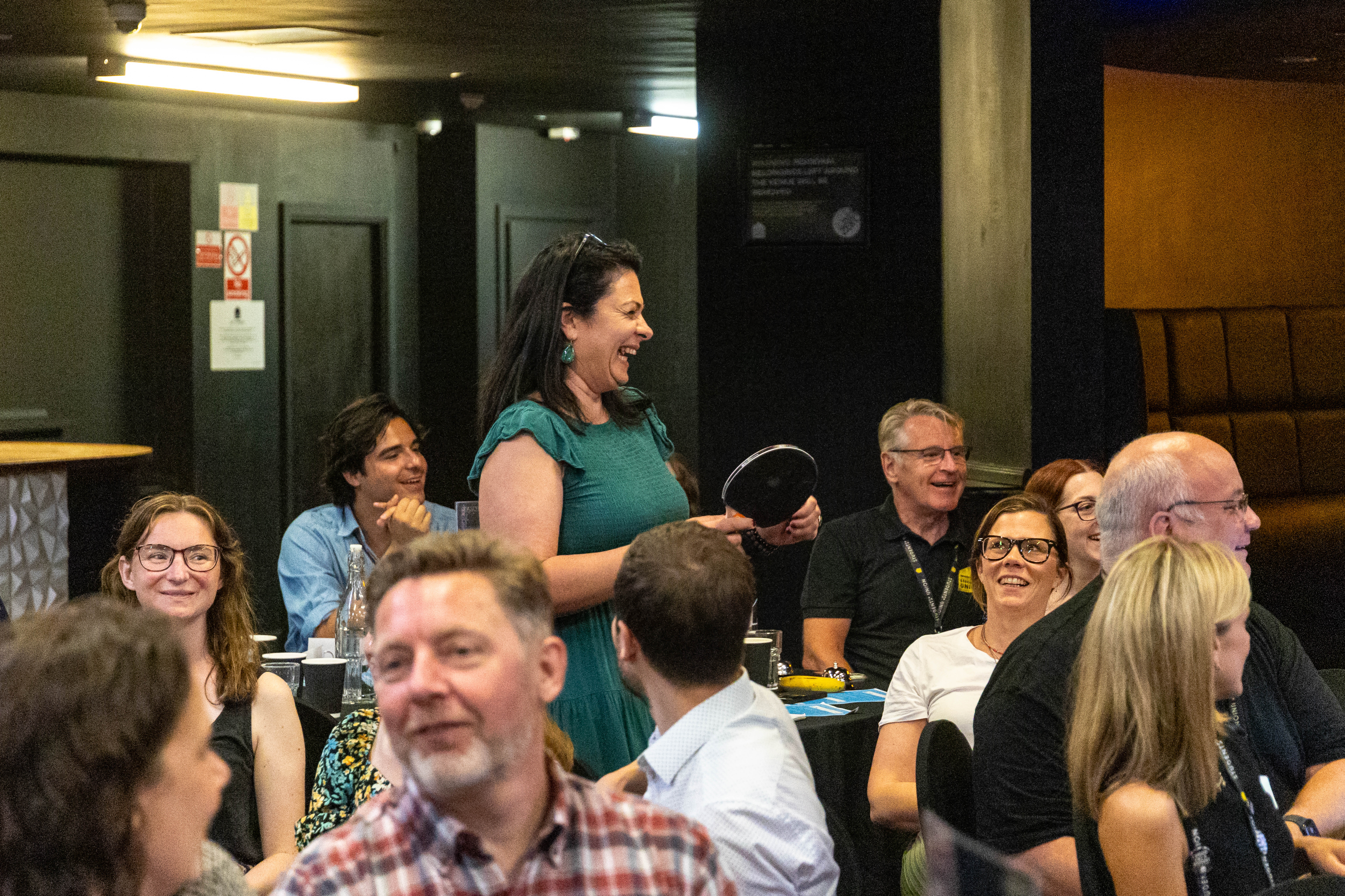 Delegates at our Student Experience Conference.  One is standing up and holding a ping-pong racket. 