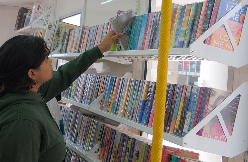 a student browses the shelves in the Essex County Council Library Services mobile library bus on campus