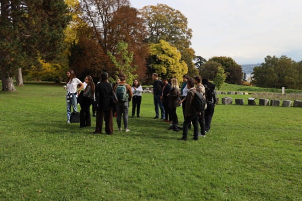 A group of people standing outside looking at a sapling which was grown from a tree that survived the atomic bomb at Hiroshima.