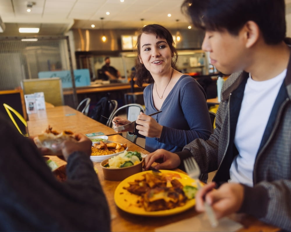two people sat at a table eating food
