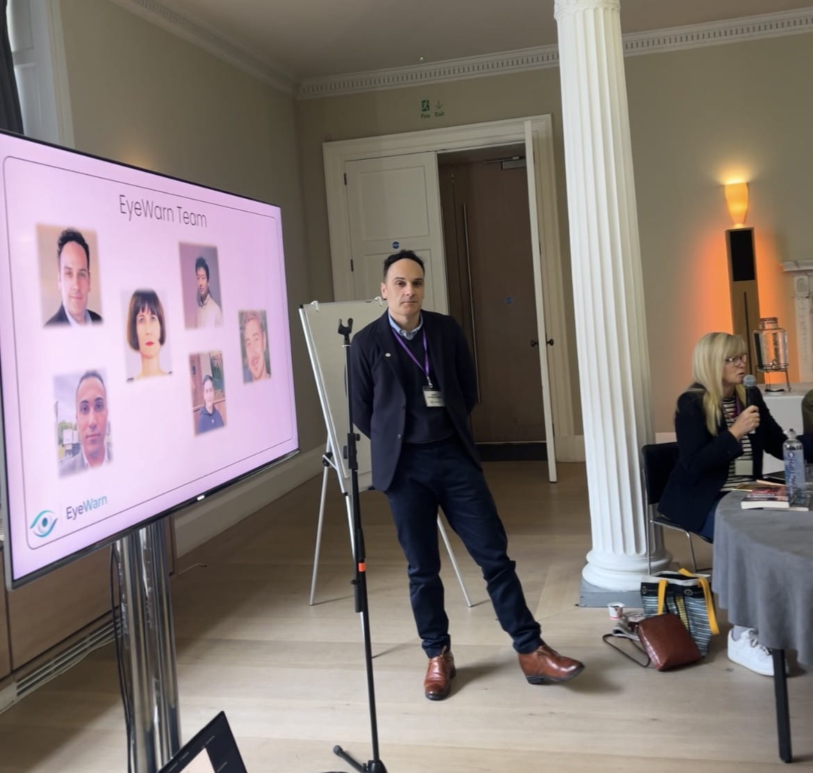 Dr Javier Andreu standing in front of a large screen showing members of the research team.