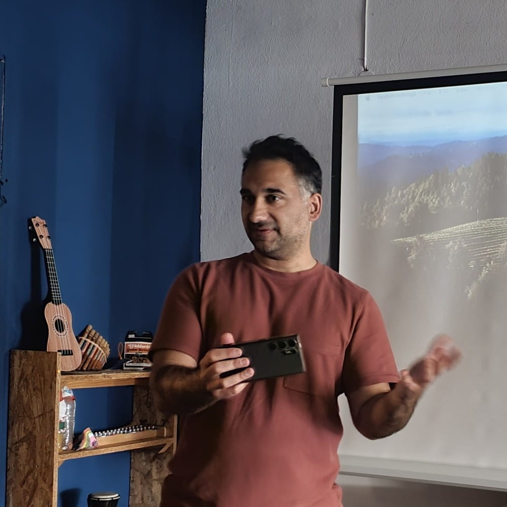 Dr Tasos Giapoutzis standing in front of a screen, holding a phone with one hand and gesturing with the other.