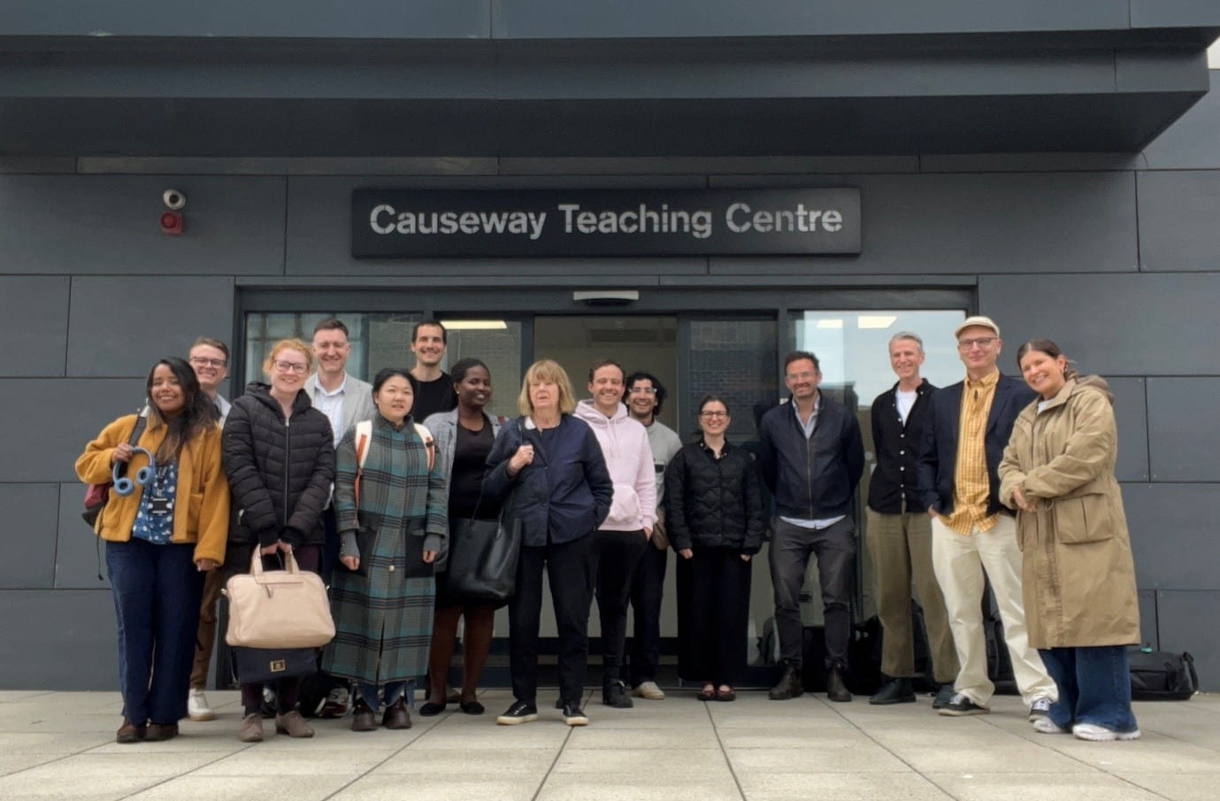 The participants of a workshop standing as a group outside the Causeway Teaching Centre. The building name is visible above them.