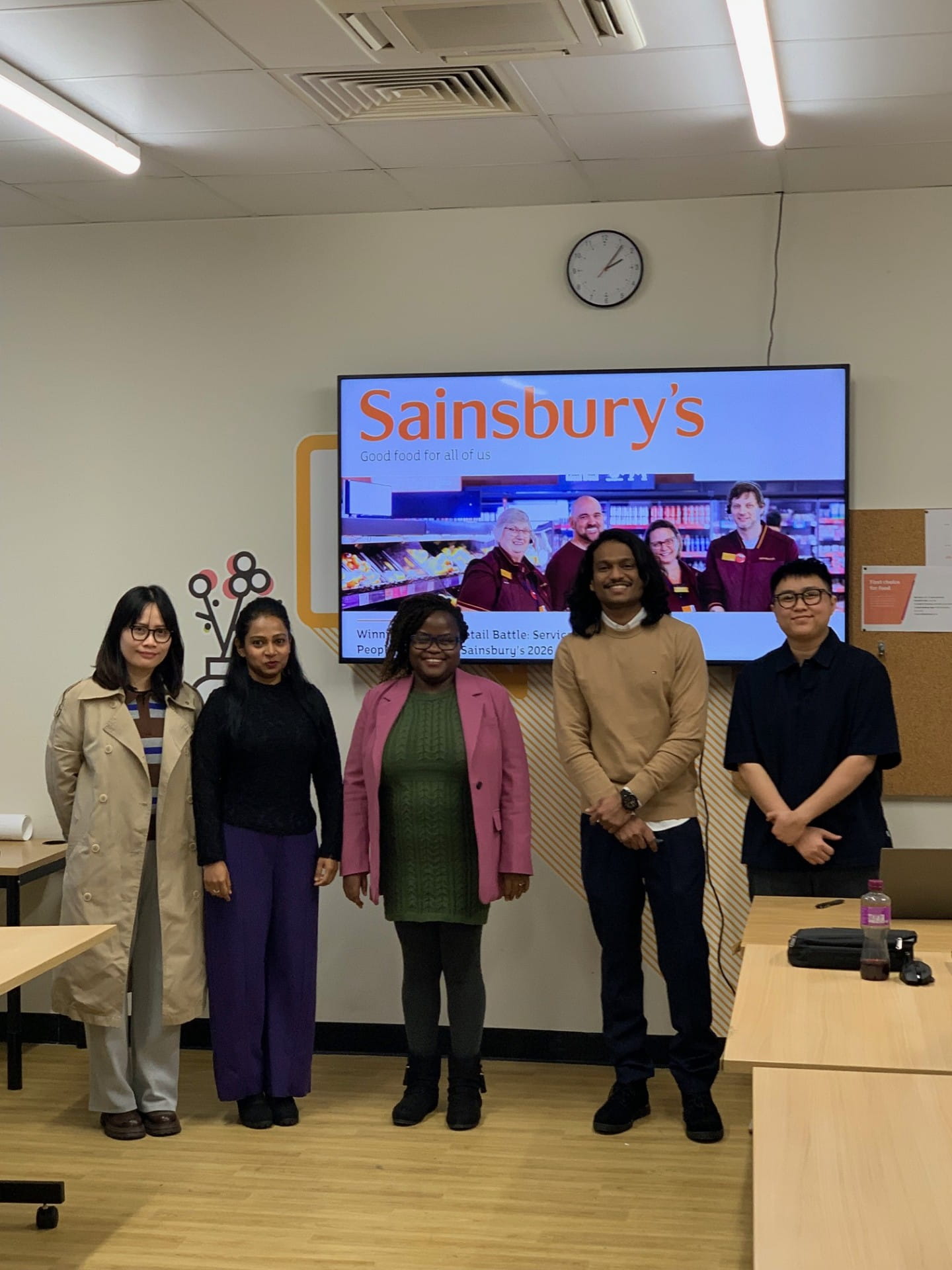 five people in front of a tv screen that reads 'sainsbury's'
