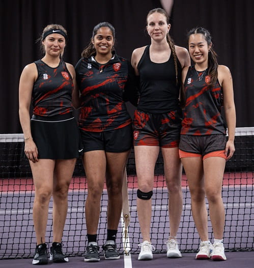 Image of University of Essex's four women's first team players posing for a photo in front of a tennis court net having reached the final of the BUCS Big Wednesday National Vase Cup image credit @sanne.hoffman.photography