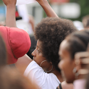 Close up photo of a group of people at a protest. Focus is zoomed in on girl 