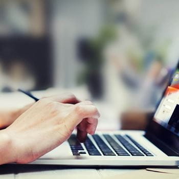 A pair of hands typing on a laptop keyboard.