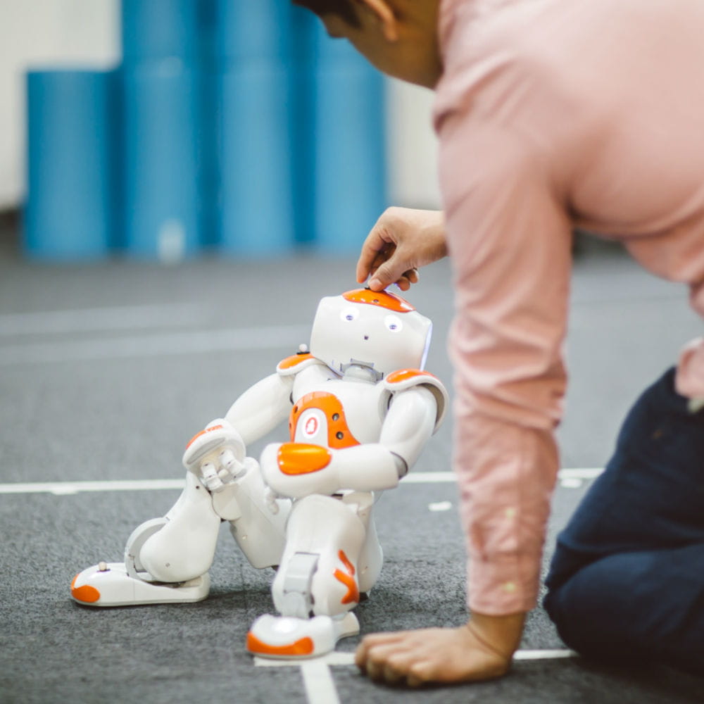 Image of a research student working with a Nao robot in our Robotics Arena.