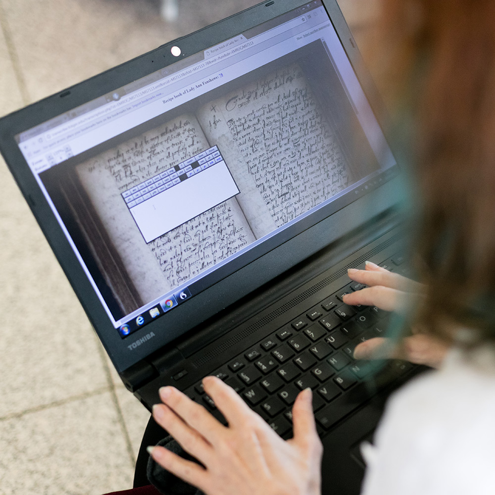 Student analyzing ancient text on a laptop