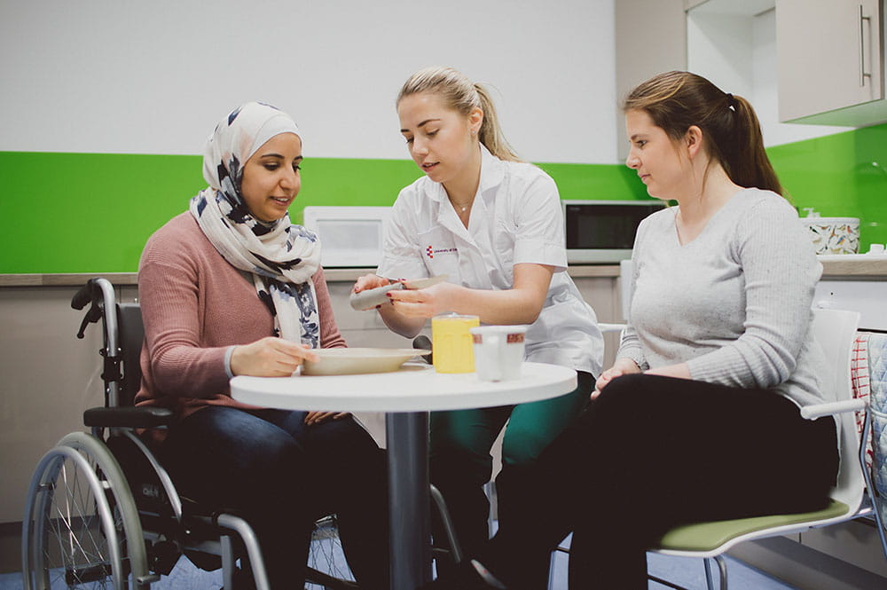 OT students practising teaching a patient how to use adapted kitchen equipment