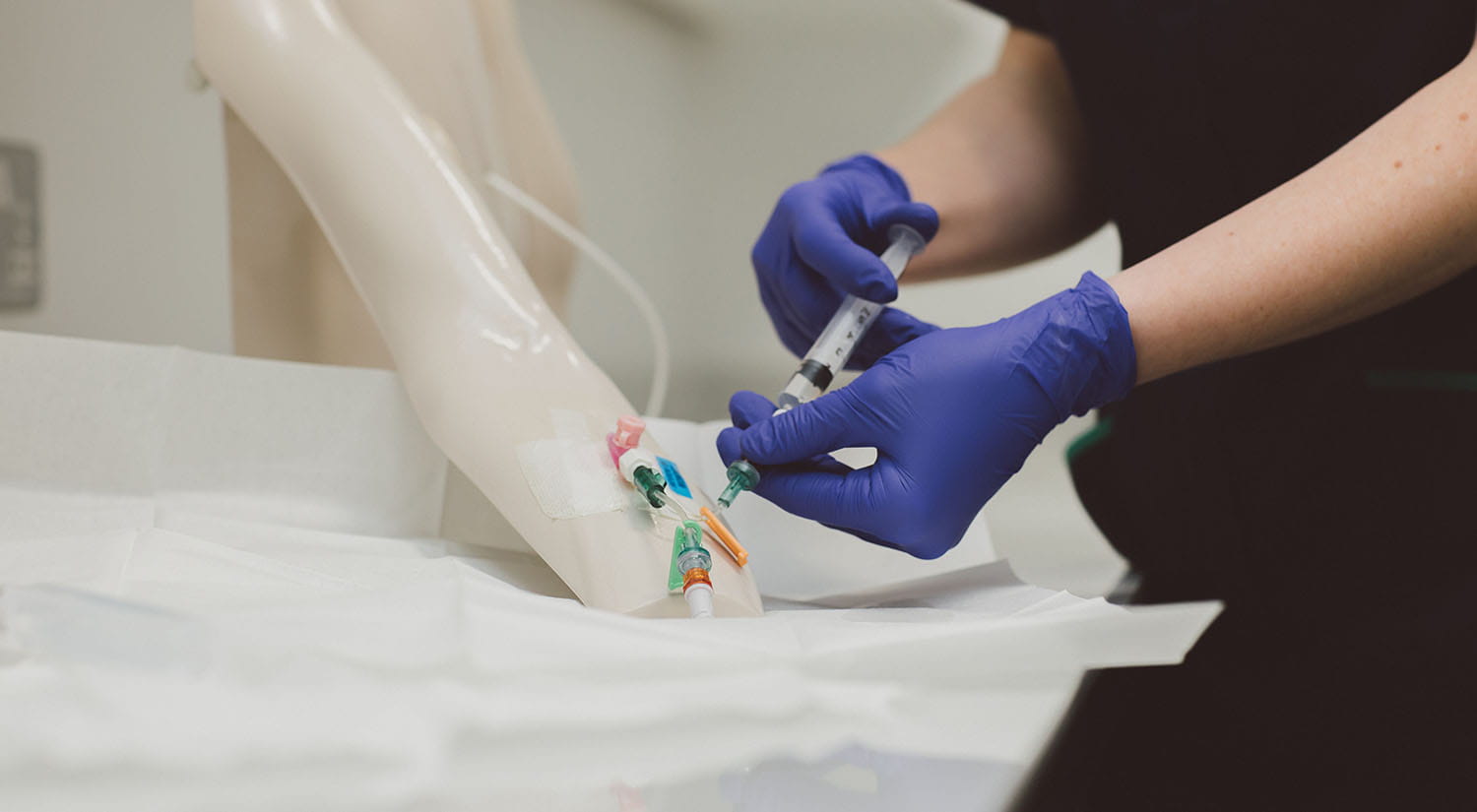 A nurse practising clinical skills on a mock arm