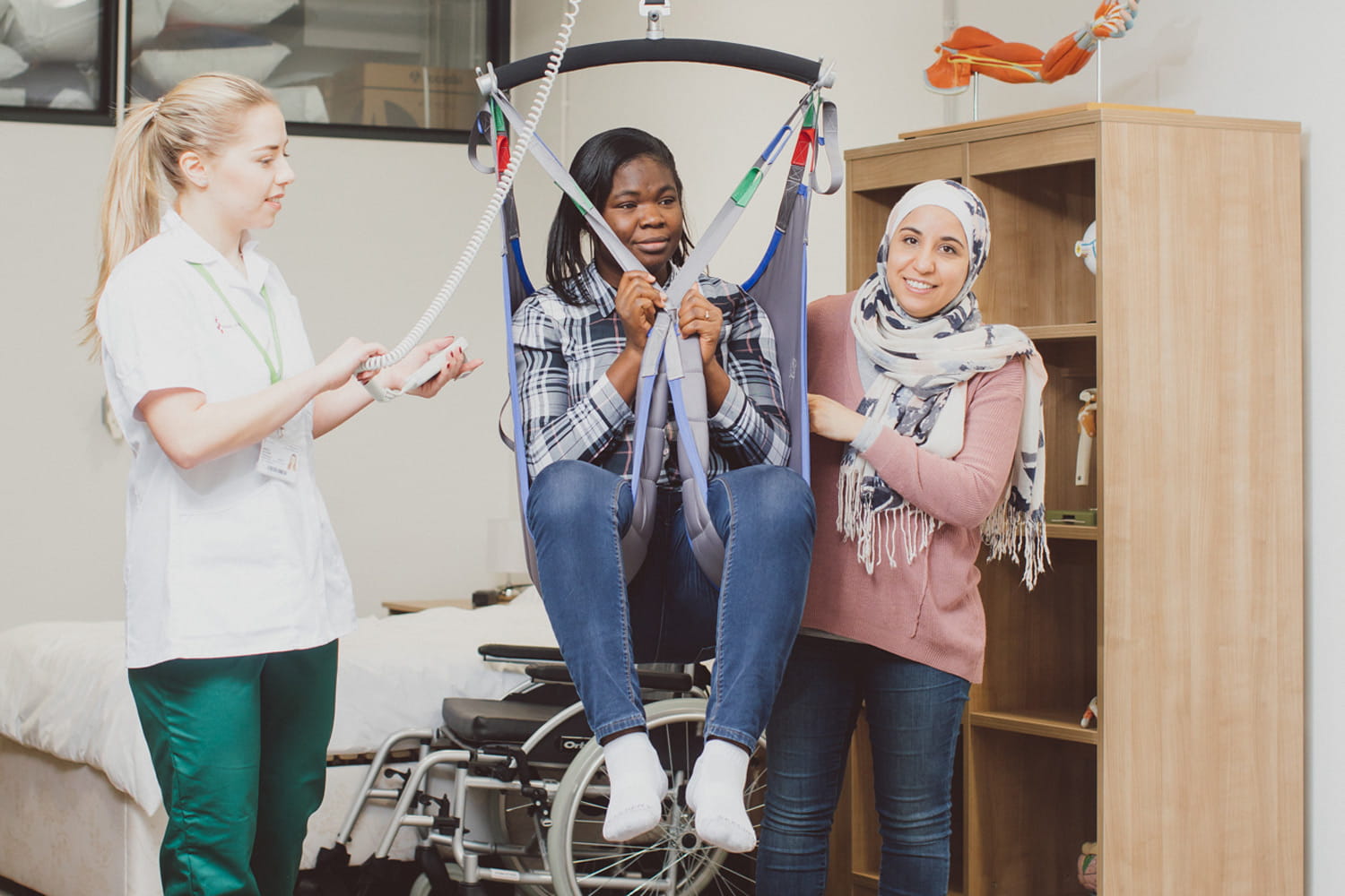 Two student Occupational Therapists moving a patient with a hoist