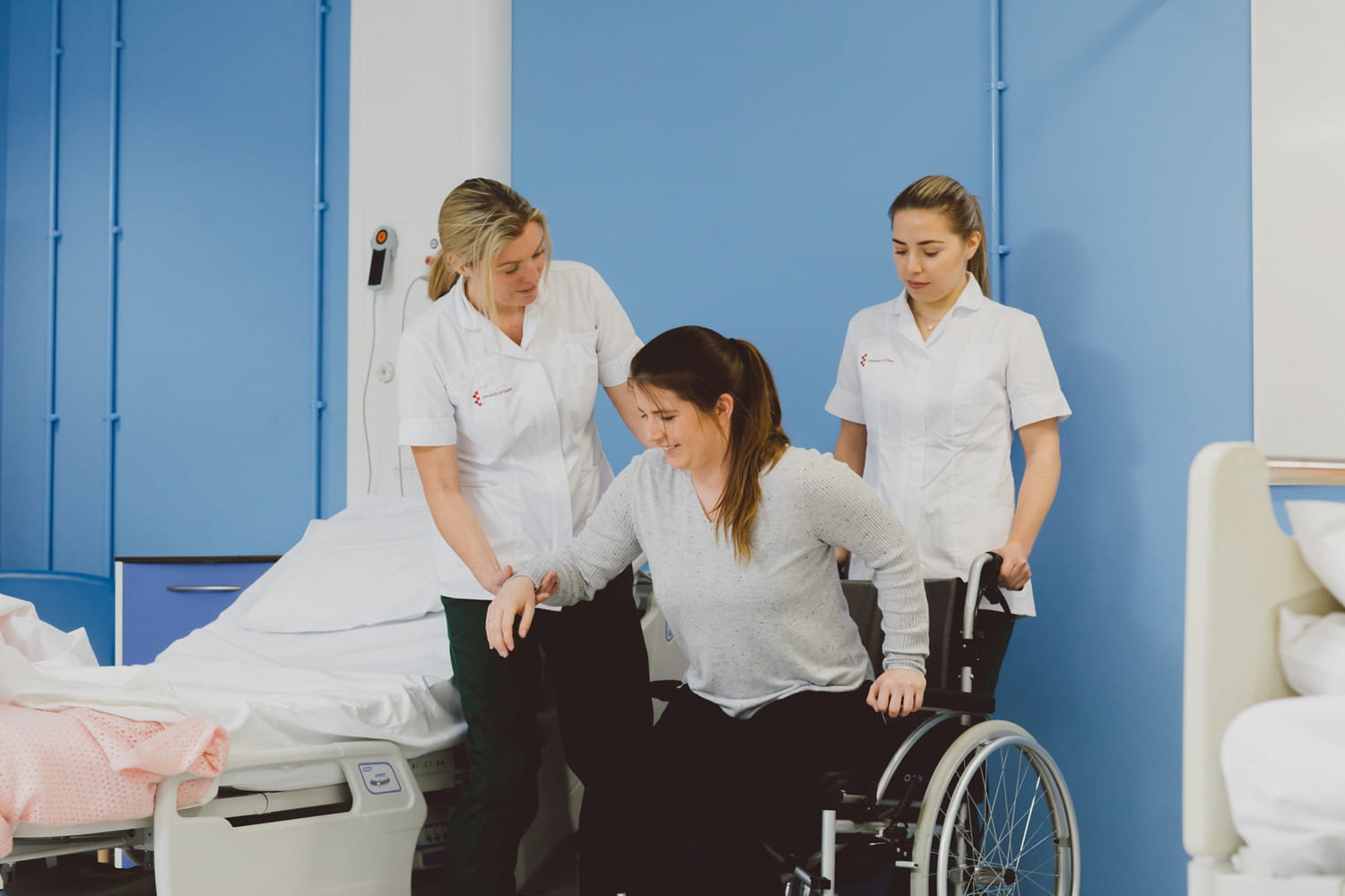 Two student Occupational Therapists helping a patient into a wheelchair