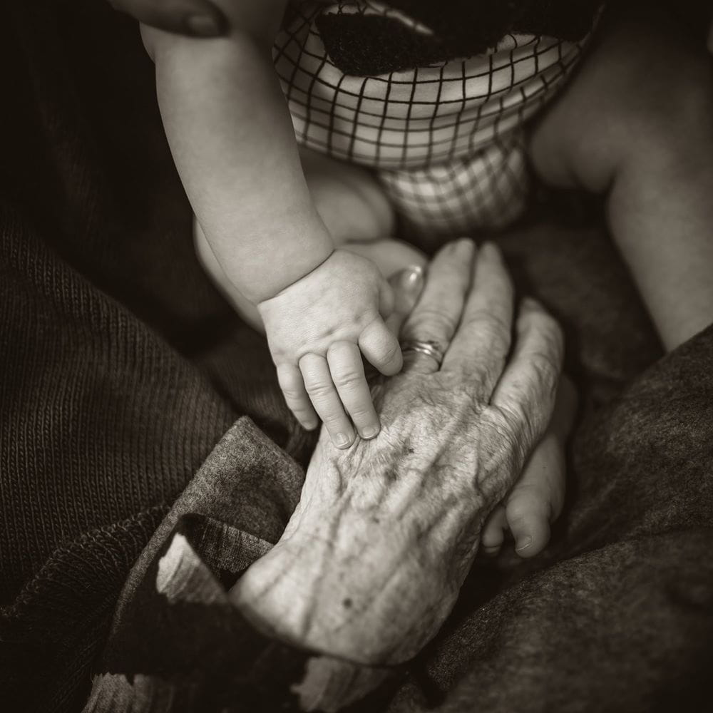 A baby and an elderly person holding hands