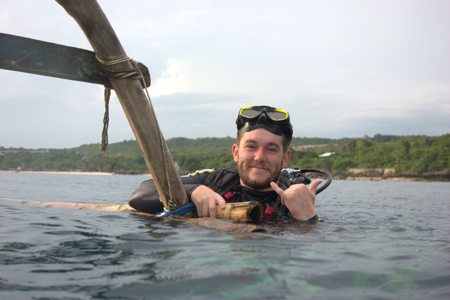 smiling scuba diver waving above water
