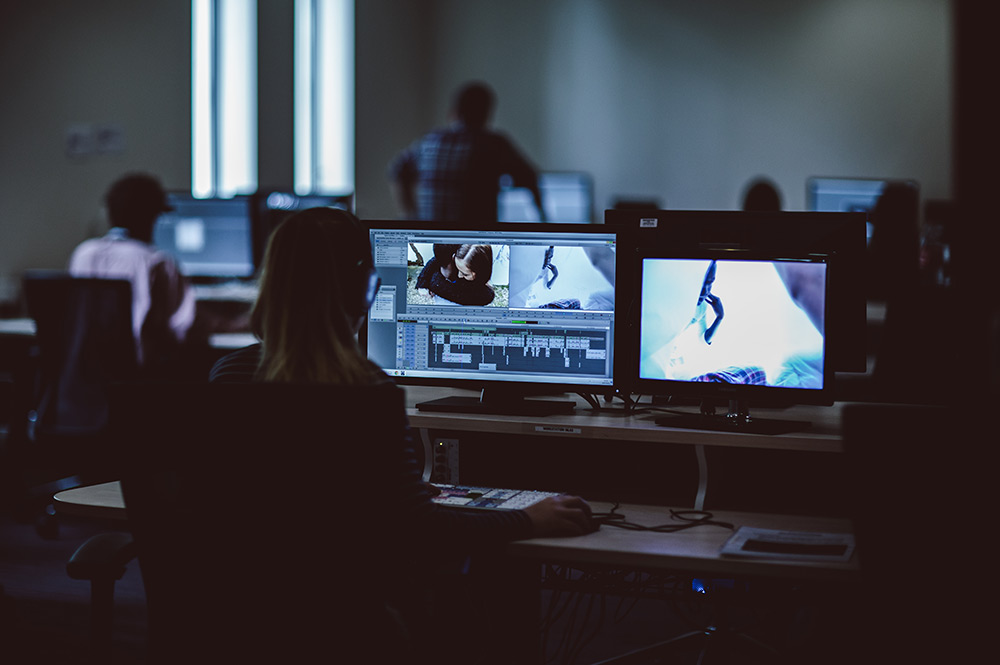 Female student on a computer in the media centre editing film footage