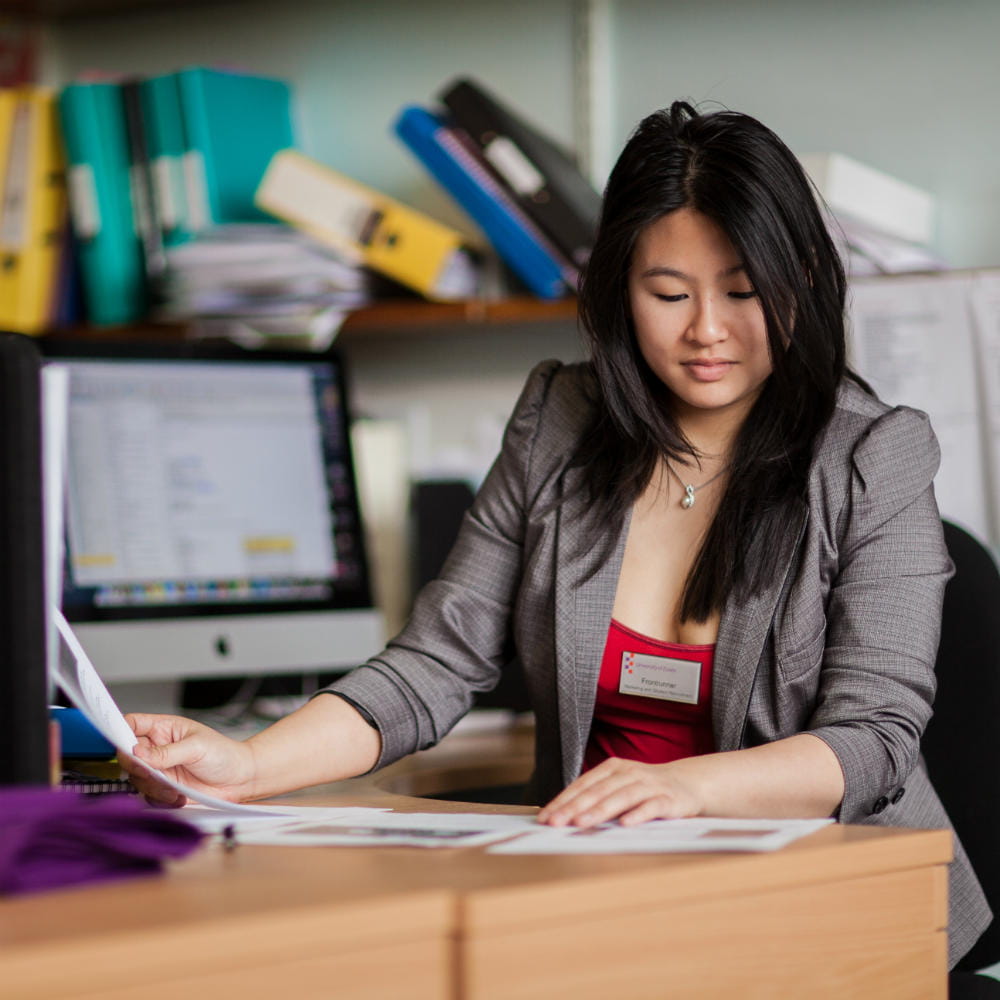 A woman sitting at a desk looking at some papers.