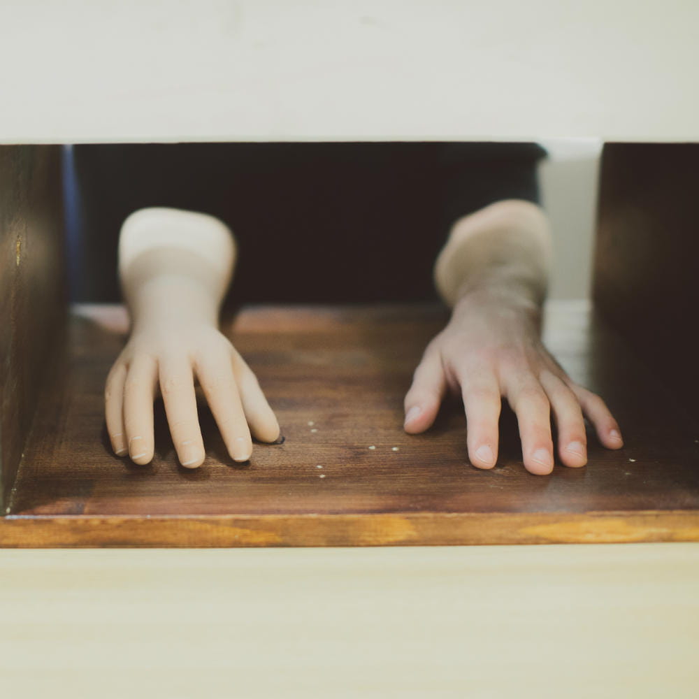 A pair of hands resting on the surface of a table.