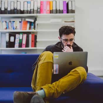 Law research student looking at laptop in Law PhD space