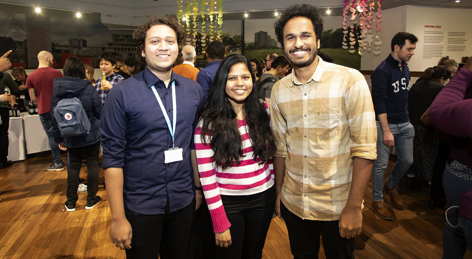 Two men and a woman posing together in a line for a photograph