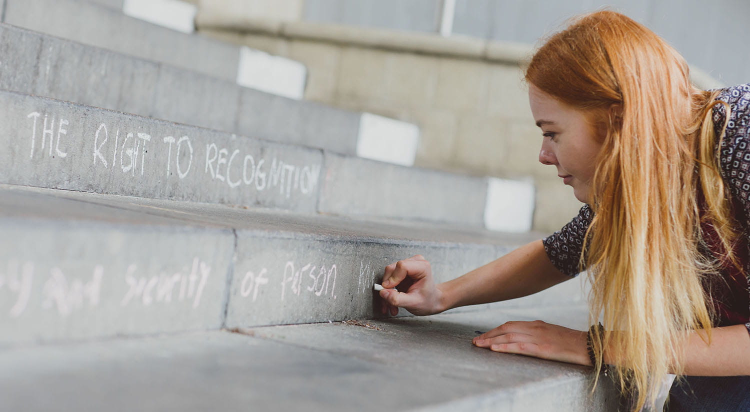 Female writing a message with chalk on outdoor steps 