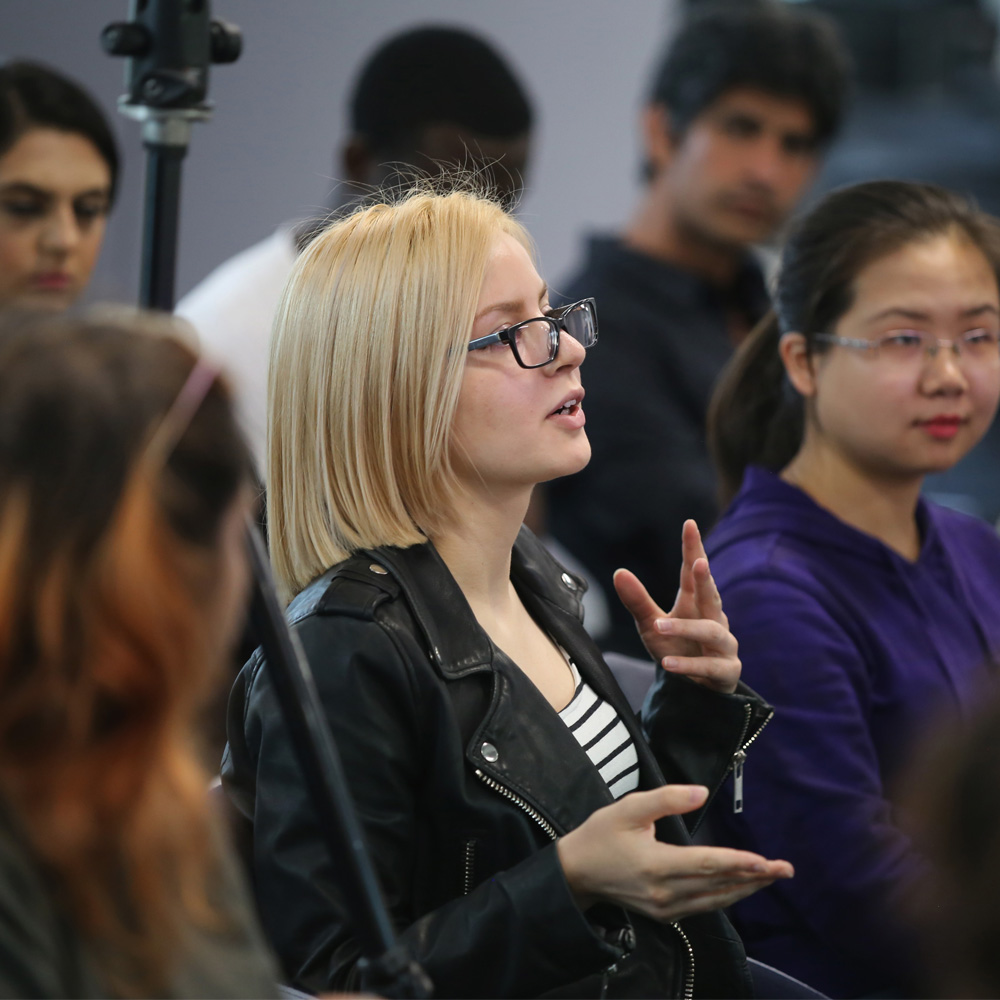 A lady sits at a networking event speaking animatedly 