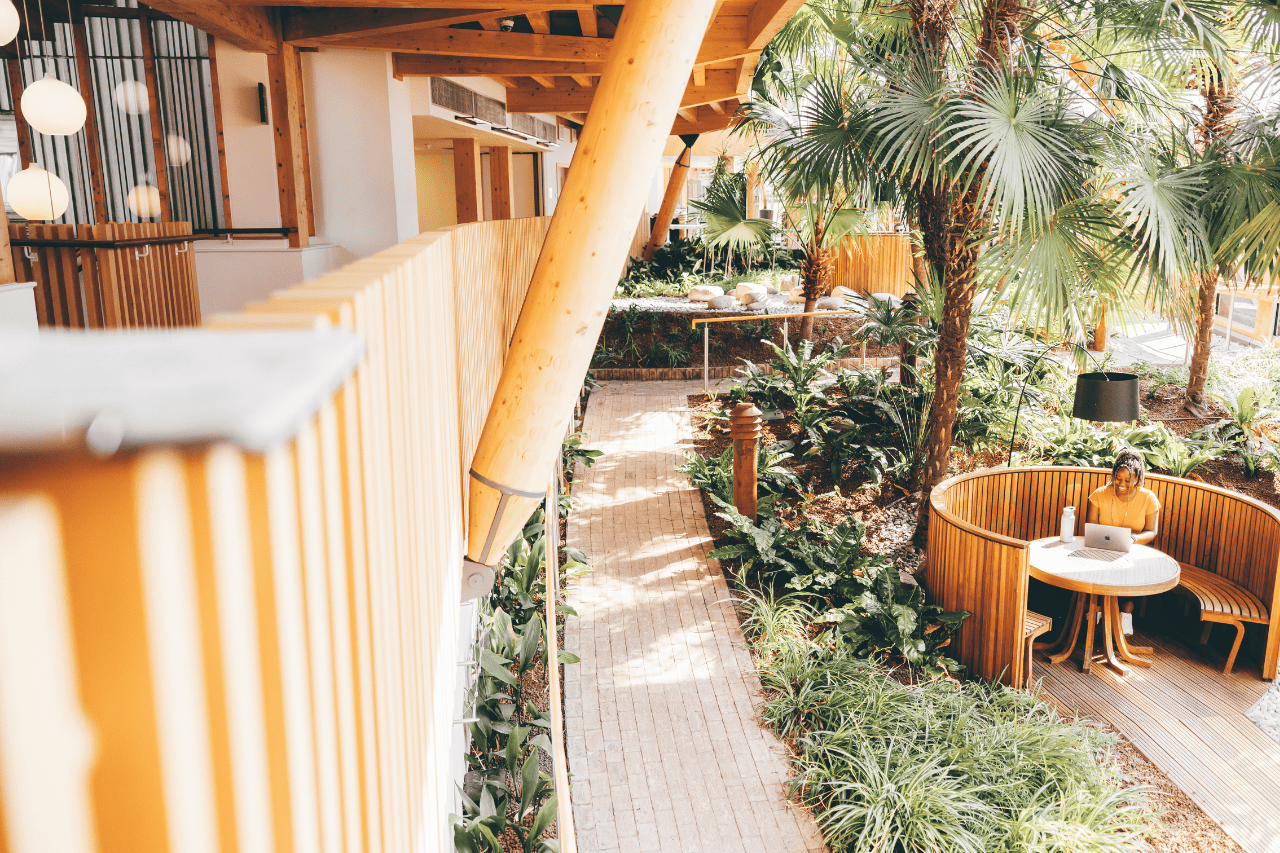 Student sat around a wooden table surrounded by the winter garden. 