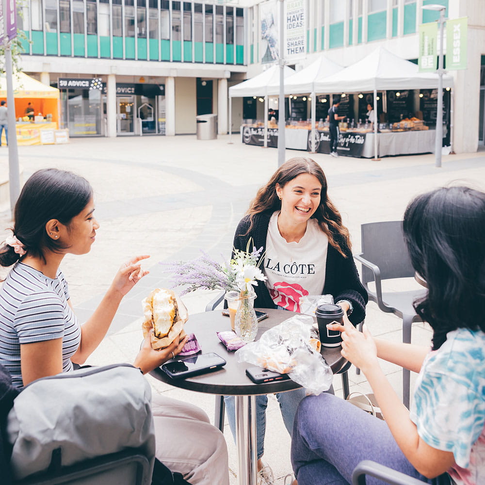 Students drinking and eating outside on the Colchester Campus squares