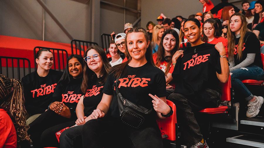 Female students watching a Rebels game wearing black and red Tribe tshirts
