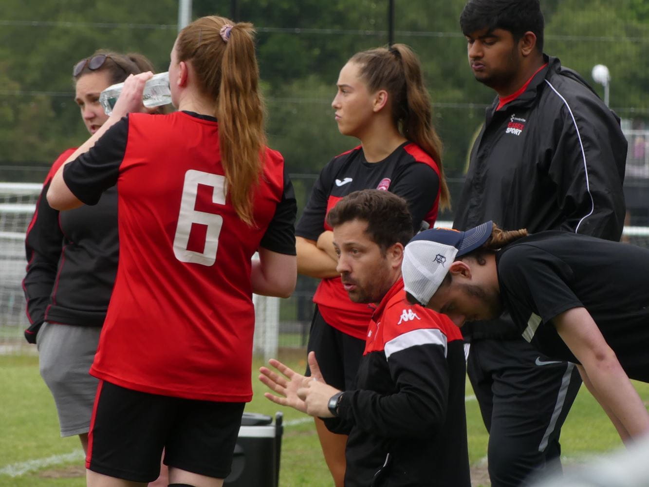 Women's football team receiving instructions from their coach.