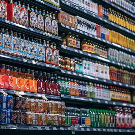 Supermarket shelves covered with rows of brightly coloured cans and bottles of drinks.