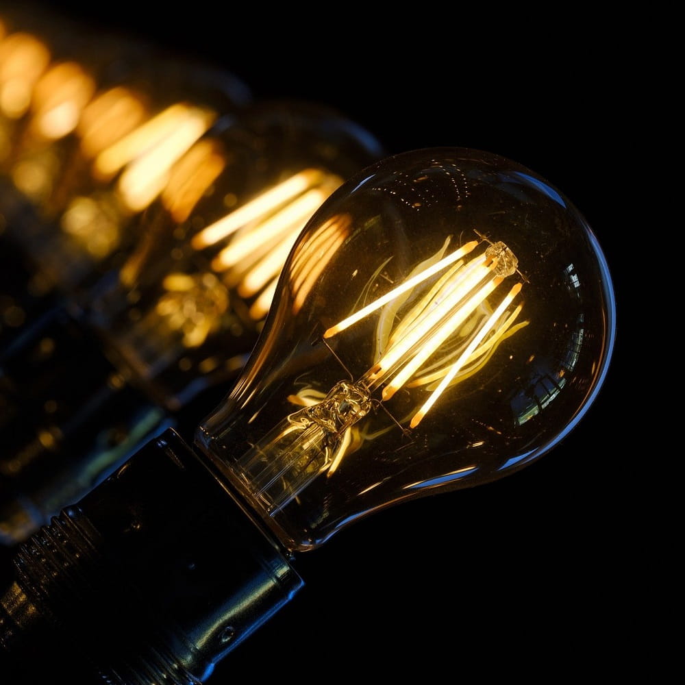 A row of lit lightbulbs against a black background.