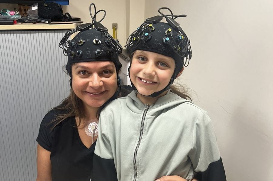 A woman and child wearing caps with sensors on.