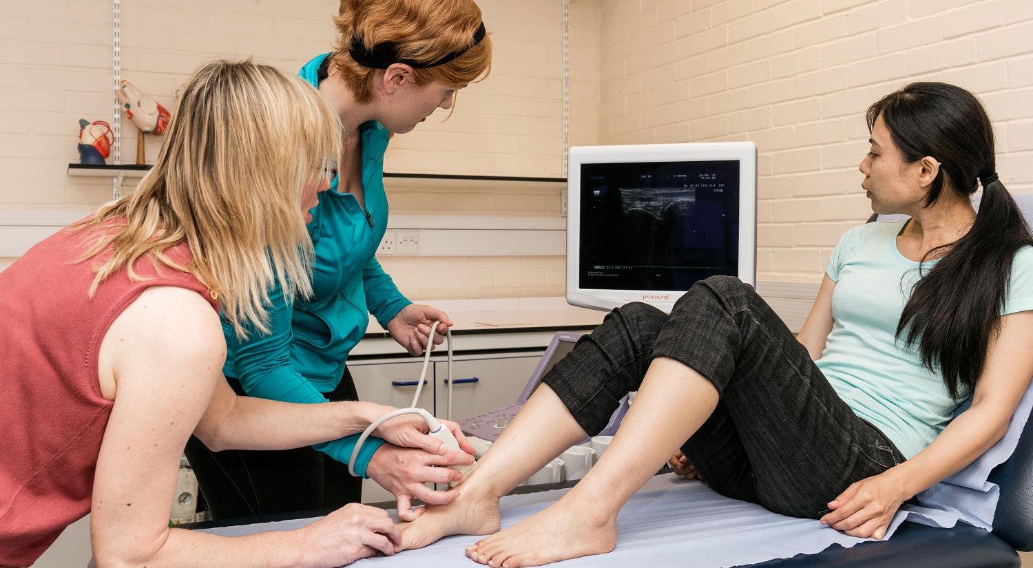 A student and teacher using ultrasound to examine a patient's foot.