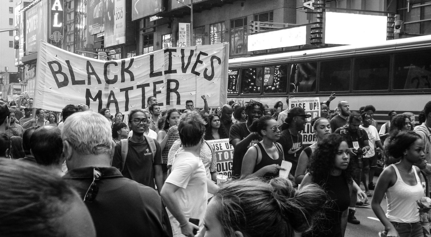 A black lives matter march on a busy street in an American city.