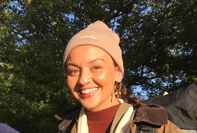 Headshot of Lora Aziz. Lora is smiling at the camera, and there's a canopy of trees behind them.