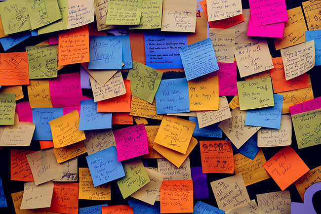 A board that has been completely obscured by countless amounts of post-its, all in different bright colours.