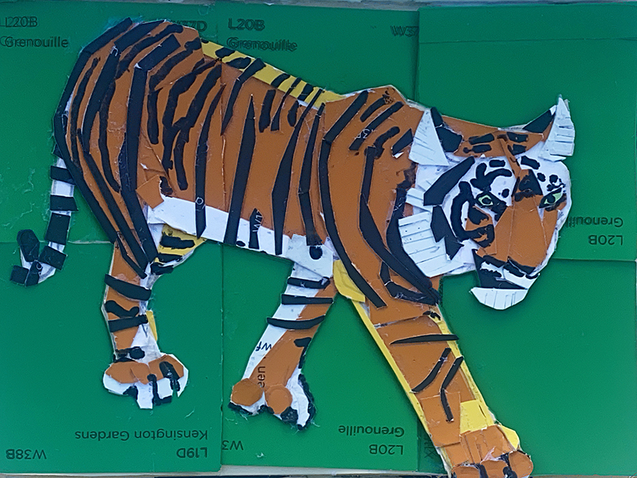 A 2D art piece made out of pieces of lino and shaped into a tiger that has its legs outstretched walking. 