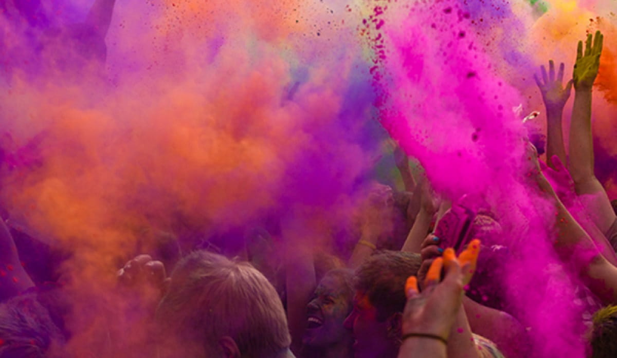 Students throwing pink and orange paint during Hindu Holi Festival)