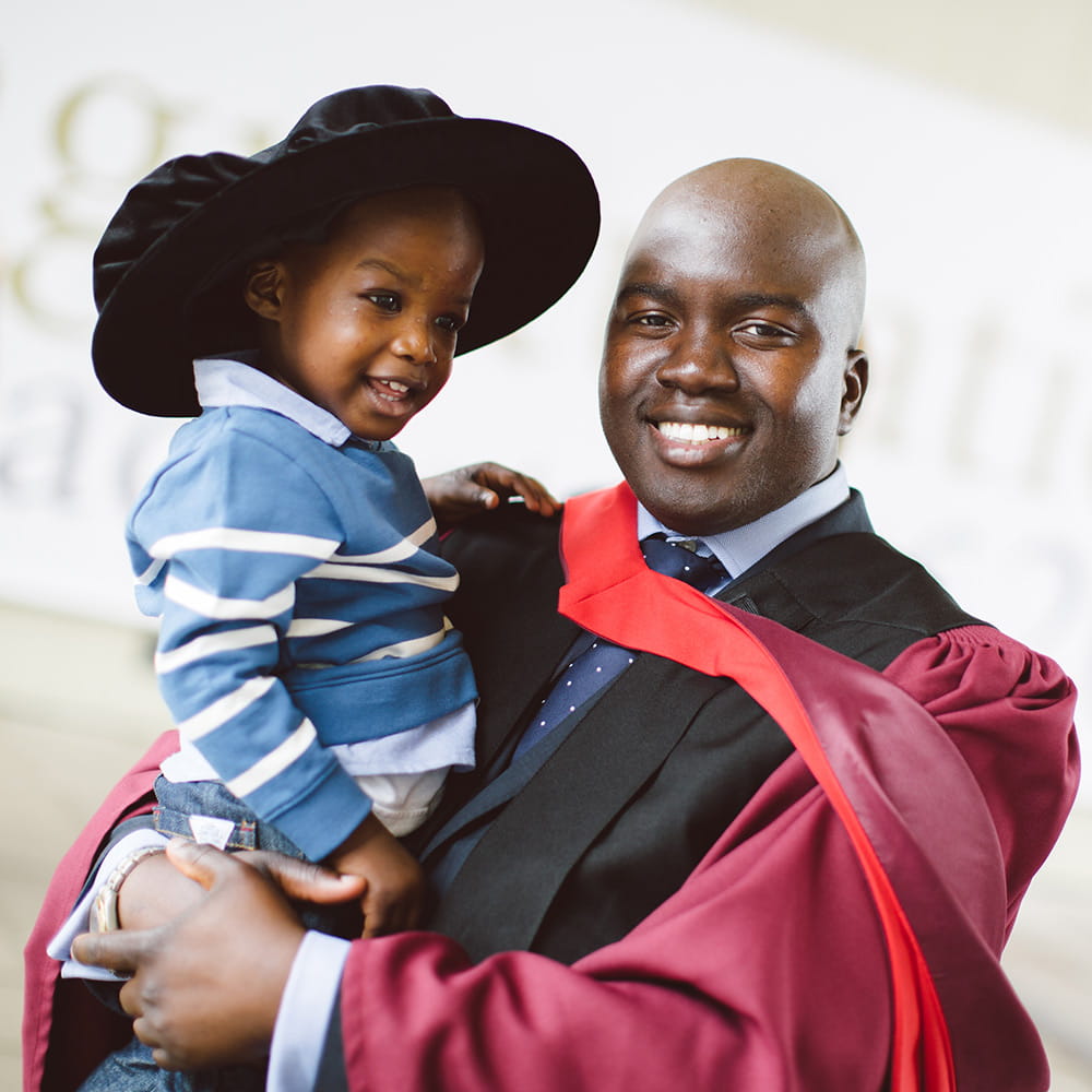 Graduate holding a young child