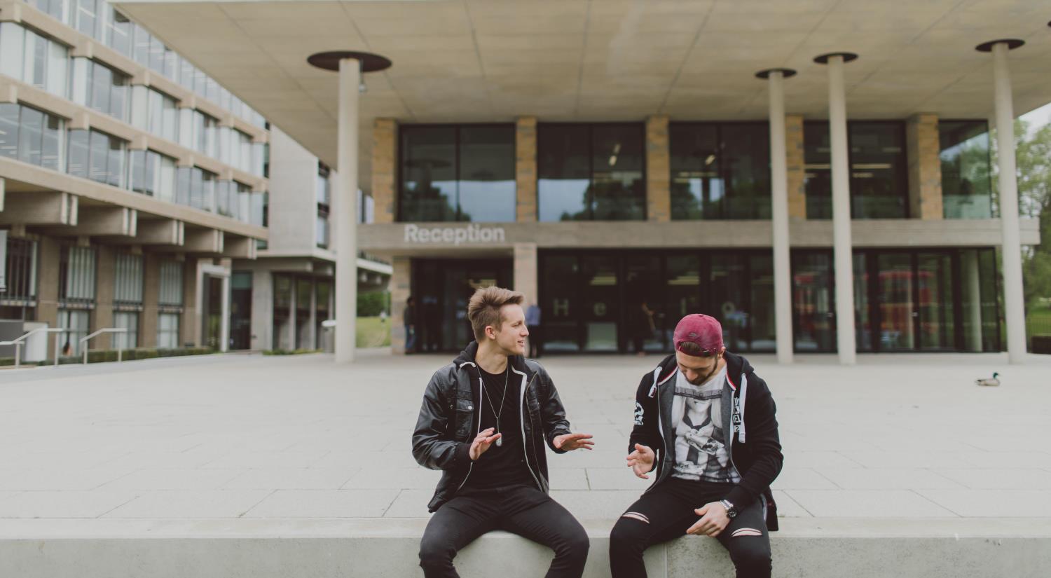 Two students sitting outside the Silberrad Student Centre on our Colchester Campus