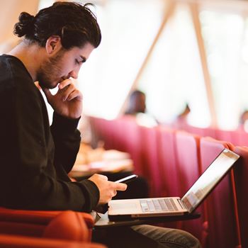 Student on laptop and phone in lecture theatre
