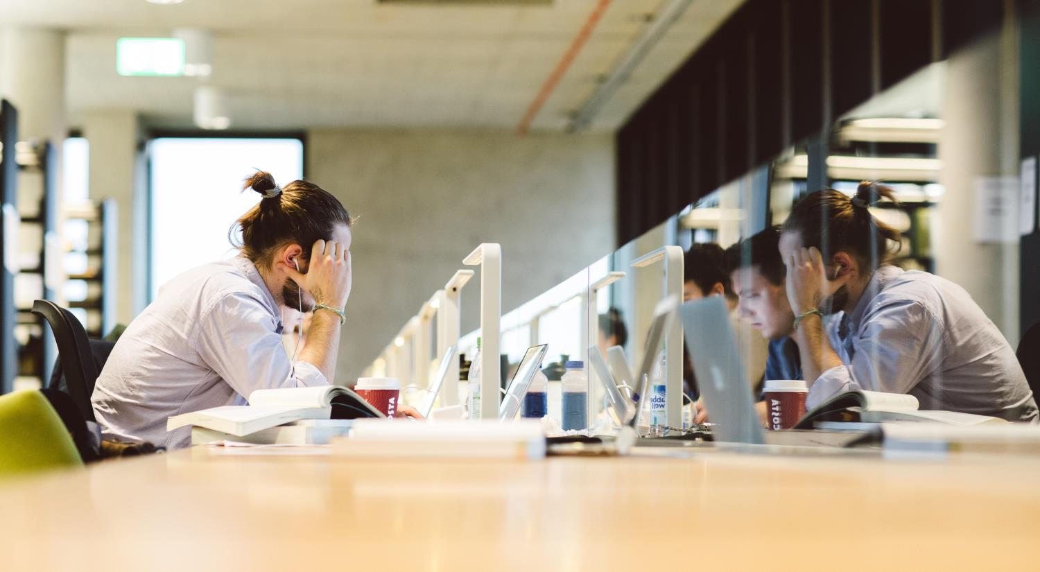 Several students working at desks in the library