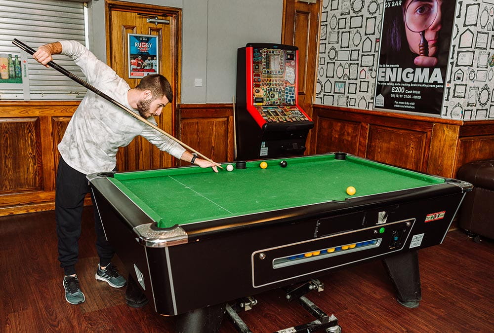 Student playing pool in the SU Bar)