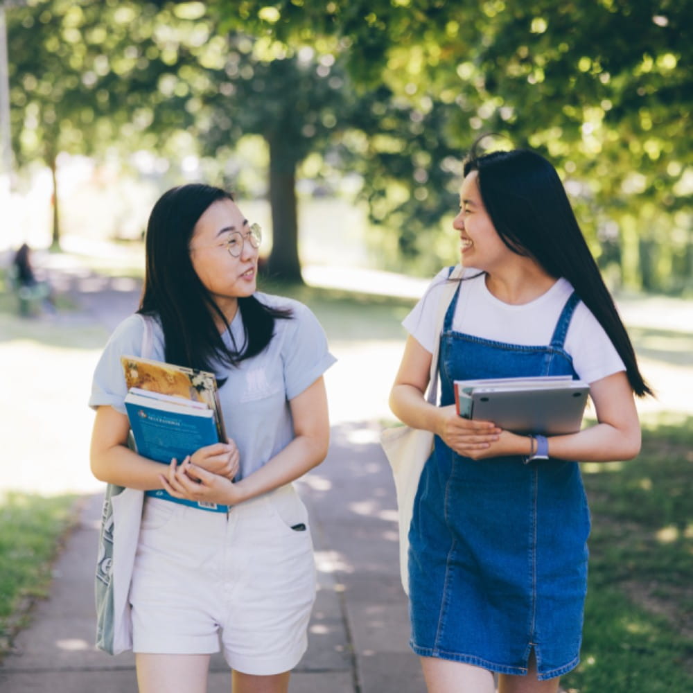 two girls facing eachother and smiling while walking