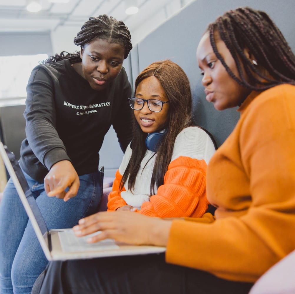 3 students looking at a laptop