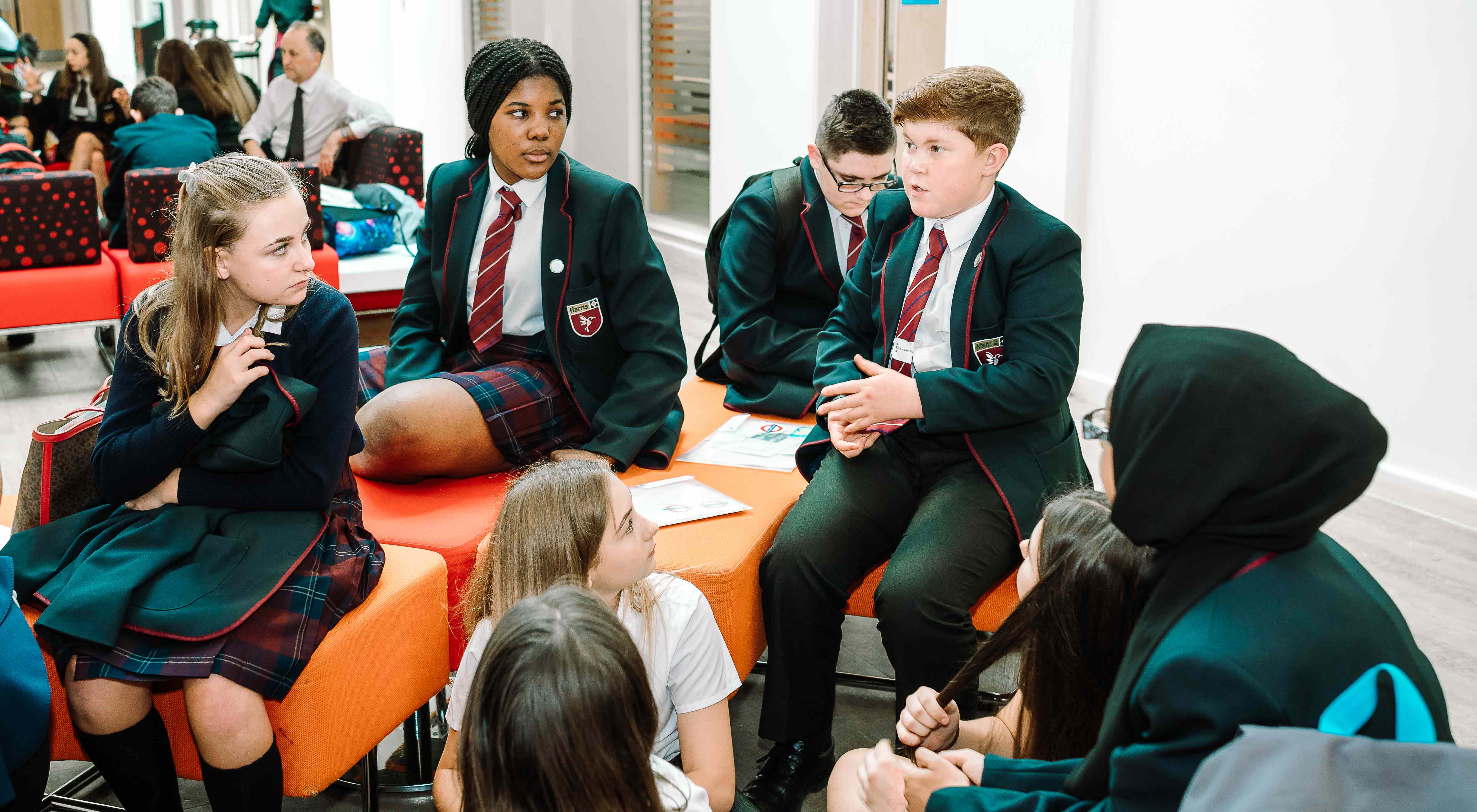 A group of young children, all wearing school uniform, sit together having a discussion