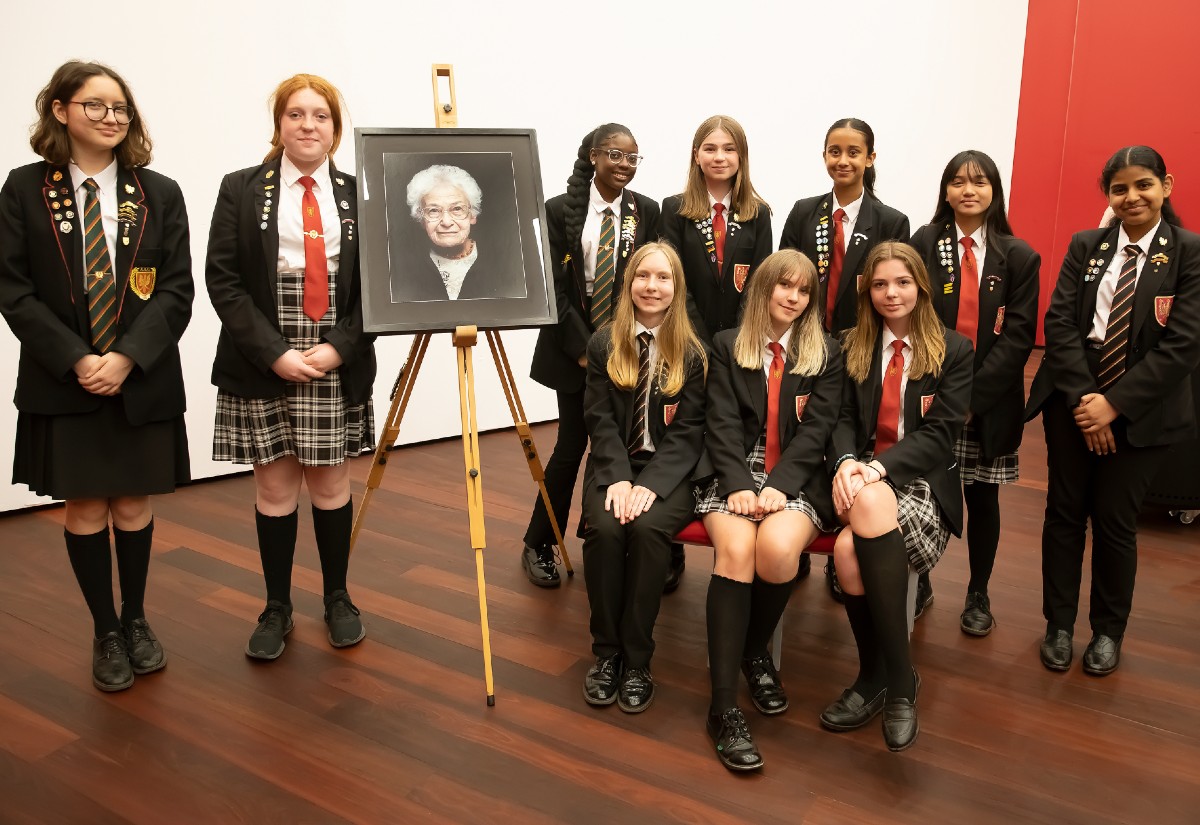 The Gilberd School team next to a portrait of Dora Love